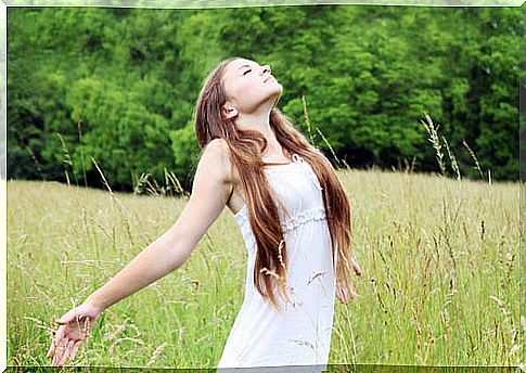 Young woman filling her lungs with air in a meadow.