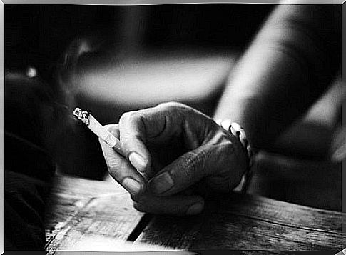 Hand holding a lit cigarette.