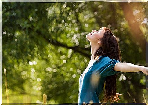 Happy woman opening her arms in the sun.