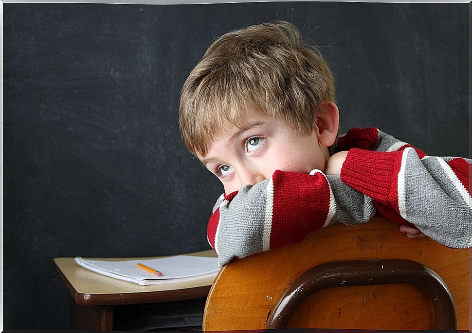 Child sitting at a desk without paying attention to homework.